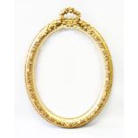 A DECORATIVE OVAL GILT FRAMED MIRROR, 20TH CENTURY, with ribbon work cresting. 3ft 7ins high x 2ft