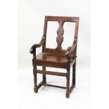 AN 18TH CENTURY OAK ARMCHAIR with square back and shaped splat, solid seat, curving arms and