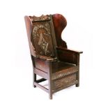 A RARE EARLY 18TH CENTURY OAK LAMBING CHAIR, with wings, panel seat and carved decoration, dated
