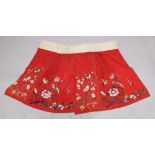 A 19TH/20TH CENTURY CHINESE EMBROIDERED RED GROUND PLEATED SILK SKIRT, decorated with birds, flowers