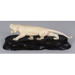 A JAPANESE MEIJI PERIOD IVORY MODEL OF A STRIDING TIGER, together with a fixed wood stand, the