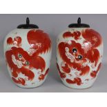 A PAIR OF EARLY 20TH CENTURY IRON-RED DECORATED PORCELAIN JARS, with fitted wood covers, each