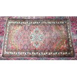 A PERSIAN RUG with central triangular motif. 5ft 5ins x 3ft 2ins.