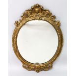 A VICTORIAN OVAL COMPOSITION GILT MIRROR. 2ft 11ins long x 1ft 9ins wide.