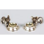 A PAIR OF SILVER PIGLETS with feeding bowl. 3.5ins long.