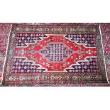 A PERSIAN RUG with large central motif in red and blue. 6ft 6ins x 4ft 2ins.