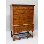 A GEORGE I WALNUT CHEST ON STAND, the top with three small doors and three long graduated drawers,