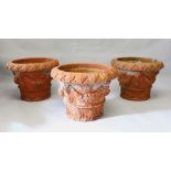 A GOOD SET OF THREE TERRACOTTA GARDEN POTS, each with moulded decoration depicting swags, flowers