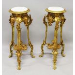 A PAIR OF GILT METAL STANDS with circular marble tops, on three curving legs. 30ins high.