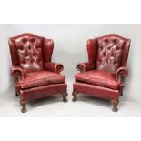 A GOOD PAIR OF GEORGE III DESIGN WING ARMCHAIRS, button upholstered in red leather, on carved paw