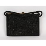 A BLACK BEADED HANDBAG, with gold tone hardware, black suede handles and sides, interior lined