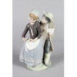 A LLADRO PORCELAIN FIGURE GROUP OF A YOUNG BOY AND GIRL "SHY", give me a kiss. 9ins high.