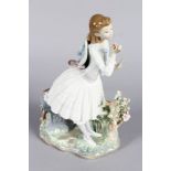 A LLADRO PORCELAIN FIGURE OF A PRETTY YOUNG GIRL with a posy, leaning against a stone seat with