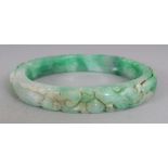 A LARGE CHINESE APPLE GREEN JADE BANGLE, the outer rim carved with lingzhi, carp, lotus, finger