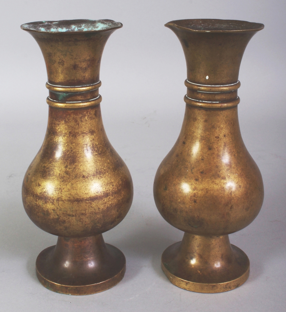 A PAIR OF 18TH CENTURY CHINESE BRONZE VASES, each supported on a high flared foot and with a