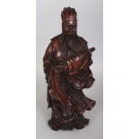 A CHINESE WOOD FIGURE OF A STANDING OFFICIAL, dressed in swirling robes and bearing a furled banner,