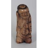 A JAPANESE MEIJI PERIOD STAGHORN NETSUKE OF A STANDING BEARDED DEITY, with cheerful expression and