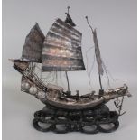 AN EARLY 20TH CENTURY CHINESE SILVER-METAL MODEL OF A JUNK, supported on a fixed & pierced lacquered