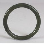 A CHINESE SPINACH GREEN JADE BANGLE, 3in diameter, the inner rim 2.25in diameter.