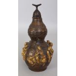 A CHINESE GILT BRONZE DOUBLE GOURD VASE & COVER, the sides cast in high relief with the Eight