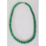 A CHINESE DARK APPLE-GREEN JADE NECKLACE, composed of spherical beads, approx. 25.25in long.