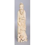 A SIGNED JAPANESE MEIJI PERIOD MARINE IVORY OKIMONO OF A STANDING MAN, bearing a fan in one hand and