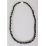 A CHINESE DARK GREEN JADE NECKLACE, composed of small spherical beads, approx. 23.25in long.