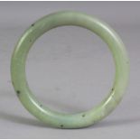 A CHINESE CELADON GREEN JADE BANGLE, 3.1in diameter, the inner rim 2.25in diameter.