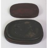 A CHINESE SHAPED BLACK INKSTONE, together with a fitted wood box, the inkstone decorated in relief