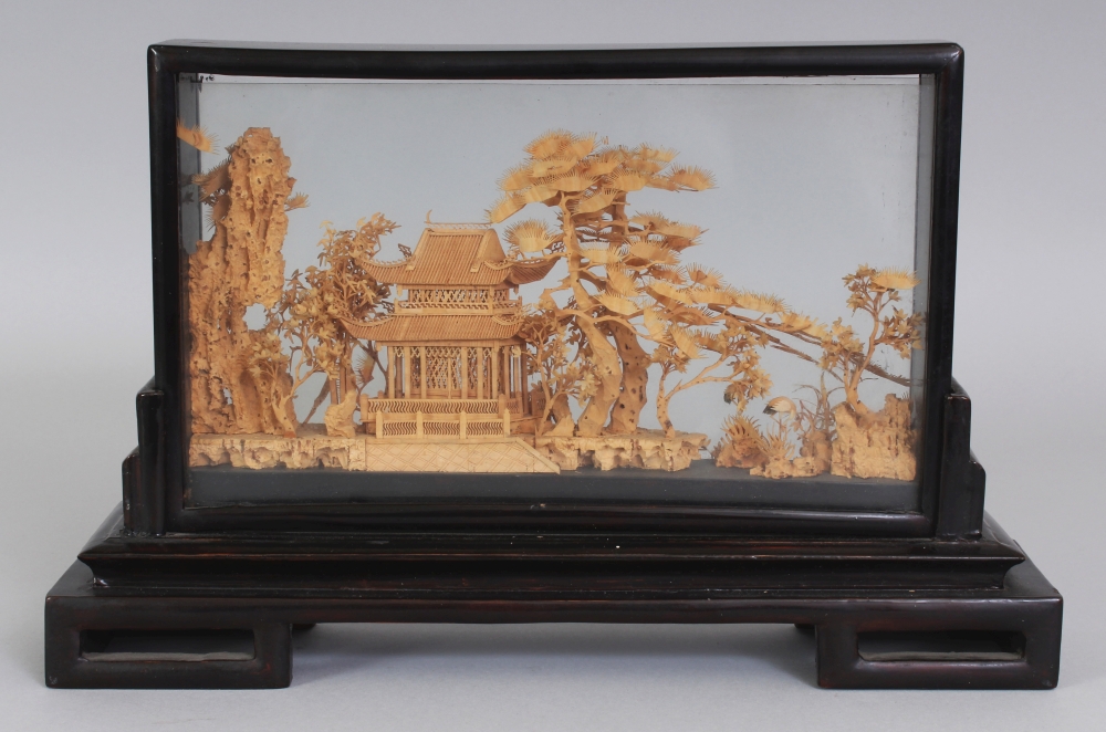 A 20TH CENTURY CHINESE CORK CARVING, in a wood and glass frame supported on a fitted rectangular