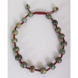 A CHINESE DARK GREEN JADE NECKLACE, with cord separated beads, approx. 21in long.