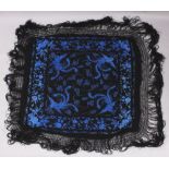 AN EARLY 20TH CENTURY CHINESE CANTON BLACK GROUND SILK SHAWL, decorated in a vivid tone of sky-