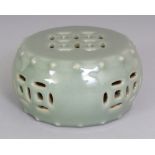 AN UNUSUAL CHINESE CELADON GLAZED MODEL OF A GARDEN SEAT, with pierced 'cash' decoration and moulded