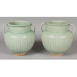 A PAIR OF CHINESE STYLE TWO-HANDLED FLUTED CELADON PORCELAIN VASES, each base with maker's marks,