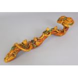 A CHINESE OCHRE GLAZED MOULDED PORCELAIN RUYI SCEPTRE, the leafage picked out in green, 13.2in