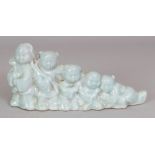 A CHINESE CELADON PORCELAIN BRUSH REST, moulded in the form of a graduated group of children, the