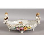 A GOOD GERMAN PORCELAIN FLOWER ENCRUSTED OVAL BASKET with flowers with two cupids. 13ins long.