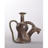 A RARE BRONZE ANTIQUITY PERFUME CONTAINER with handle and spout, terminating in the head of a horned