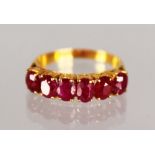 A 22CT GOLD RUBY SIX STONE HOOP RING.