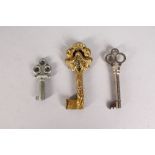 A LOVELY SMALL CAST BRONZE KEY, the handle with two cupids, 2.5ins, and TWO SILVERED KEYS, 2.