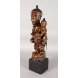 A GOOD CARVED WOOD TRIBAL FIGURE OF A MOTHER AND CHILD wearing beads, on a stand. 17.5ins high.