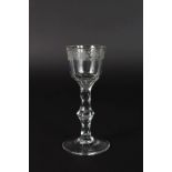 A GEORGIAN WINE GLASS with facet cut stem, the bowl engraved with fruiting vines. 6ins high.