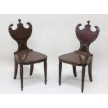 A GOOD PAIR OF REGENCY MAHOGANY SHIELD BACK HALL CHAIRS, the cresting rails with helmet and carved