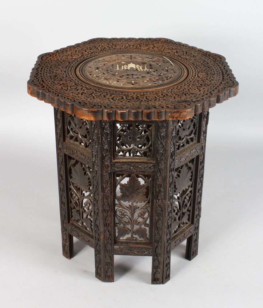 AN INDIAN CARVED COLLAPSIBLE TABLE inlaid with ivory. 16ins high.
