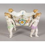 A GOOD GERMAN PORCELAIN FLOWER ENCRUSTED BOWL, painted with flowers and held by four cupids. 10ins