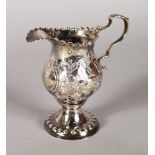A GEORGE III HELMET SHAPED CREAM JUG with floral repousse decoration. London 1774.