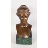 A GOOD ROMAN STYLE BUST OF A YOUNG LADY, her hair in a bun, on a green marble plinth. 1ft 6ins