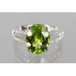 A 14K WHITE GOLD AND DIAMOND RING SET WITH AN OVAL CUT PERIDOT, approx. 3.48ctm diamonds approx. 0.