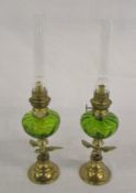 Pair of brass paraffin lamps with green glass reservoir & eagle decoration
