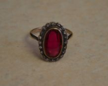 18ct gold red spinel ring surrounded by small diamonds,